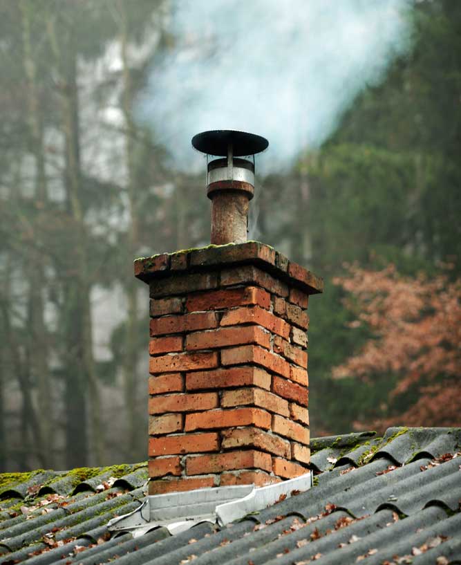 Chimney needing repairing and cleaning with smoke coming out of the top.