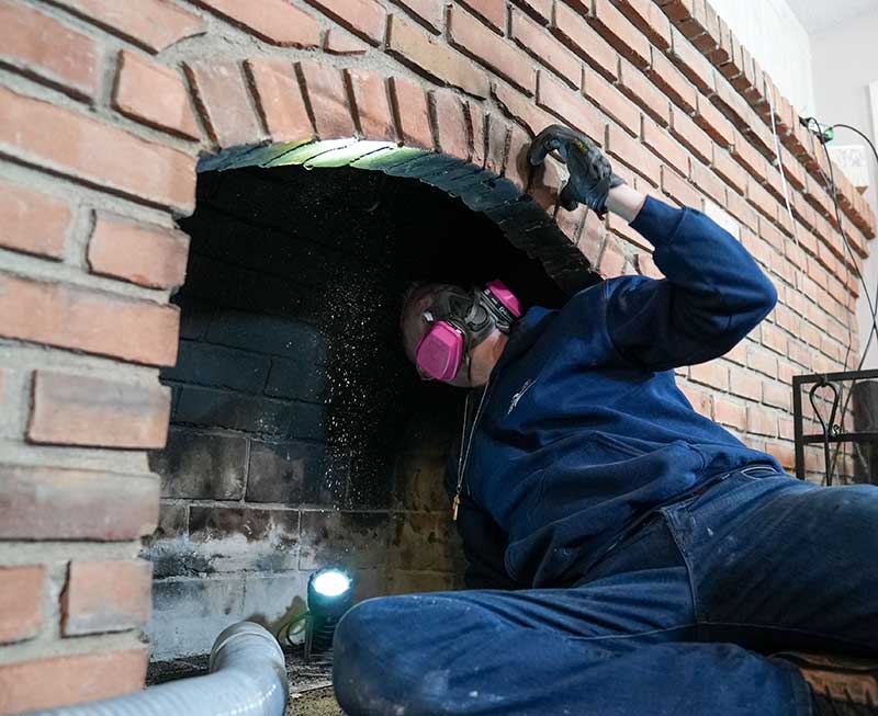 Tech wearing a mask looking up chimney with face mask.