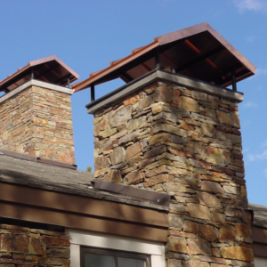 two masonry chimneys with red chimney caps